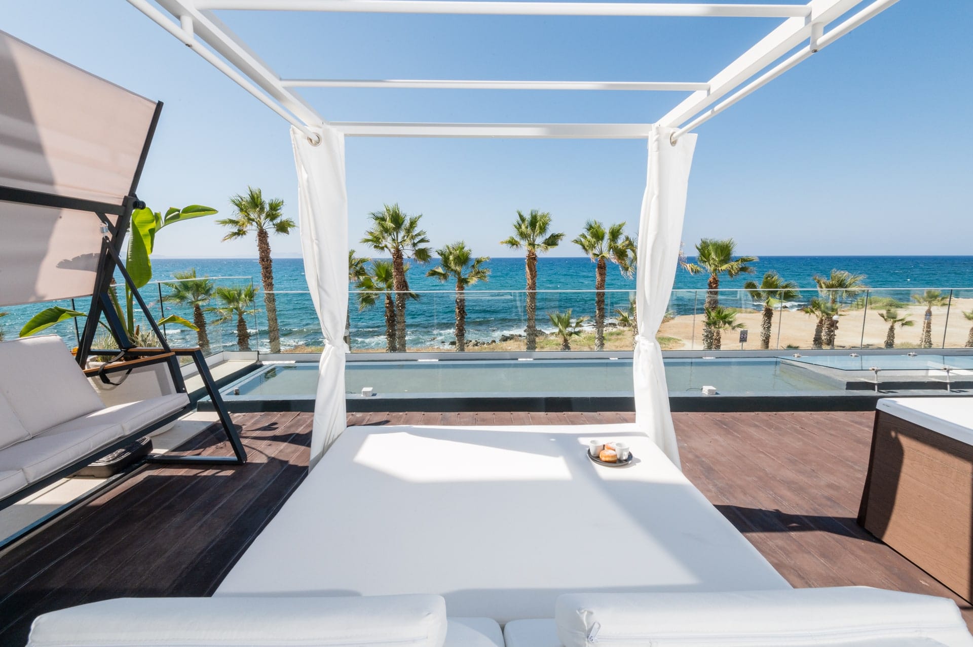 Jacuzzi and sun bed on the front deck, palms and the sea behind