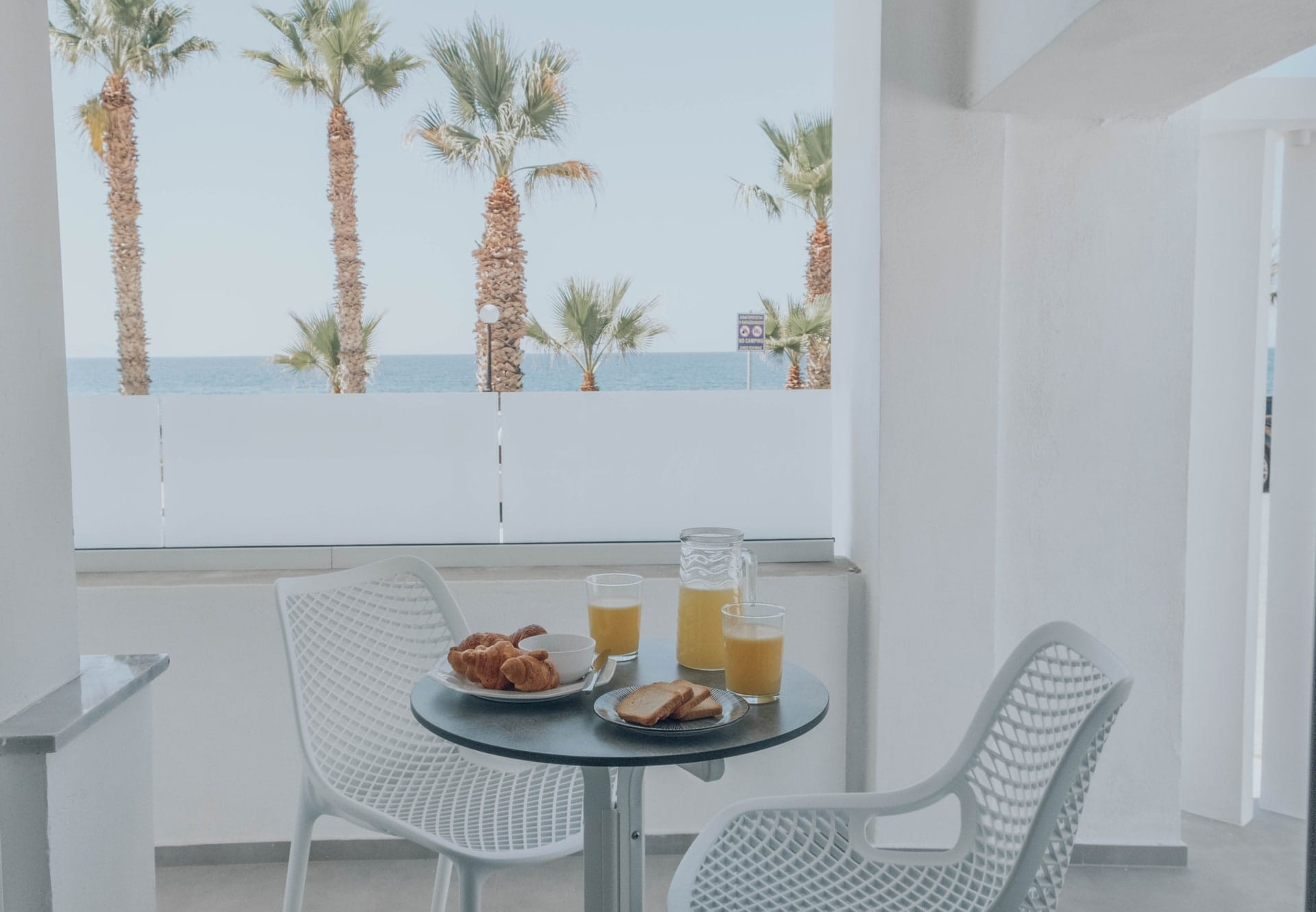 Breakfast laid on the balcony table with palms and the sea beyond