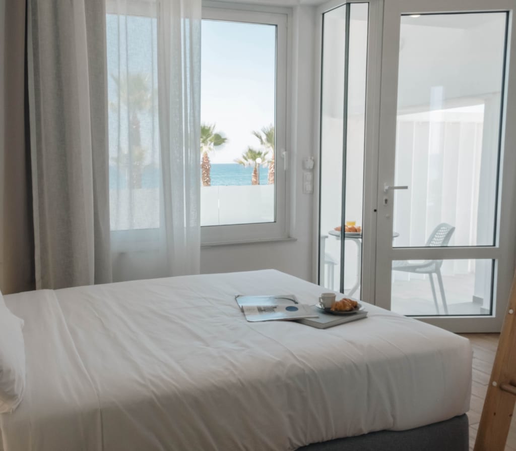 Breakfast tray on the twin bed, balcony doors open to the sea
