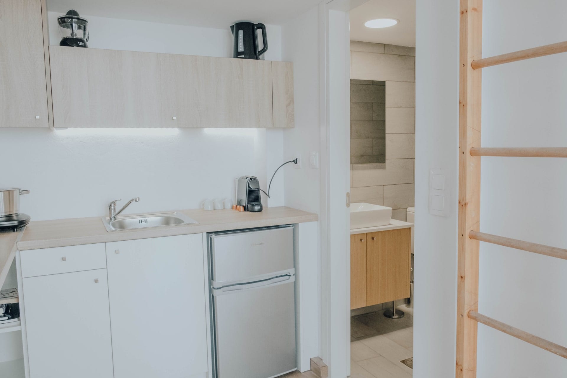 Kitchenette with refrigerator and kettle beside the bathroom door