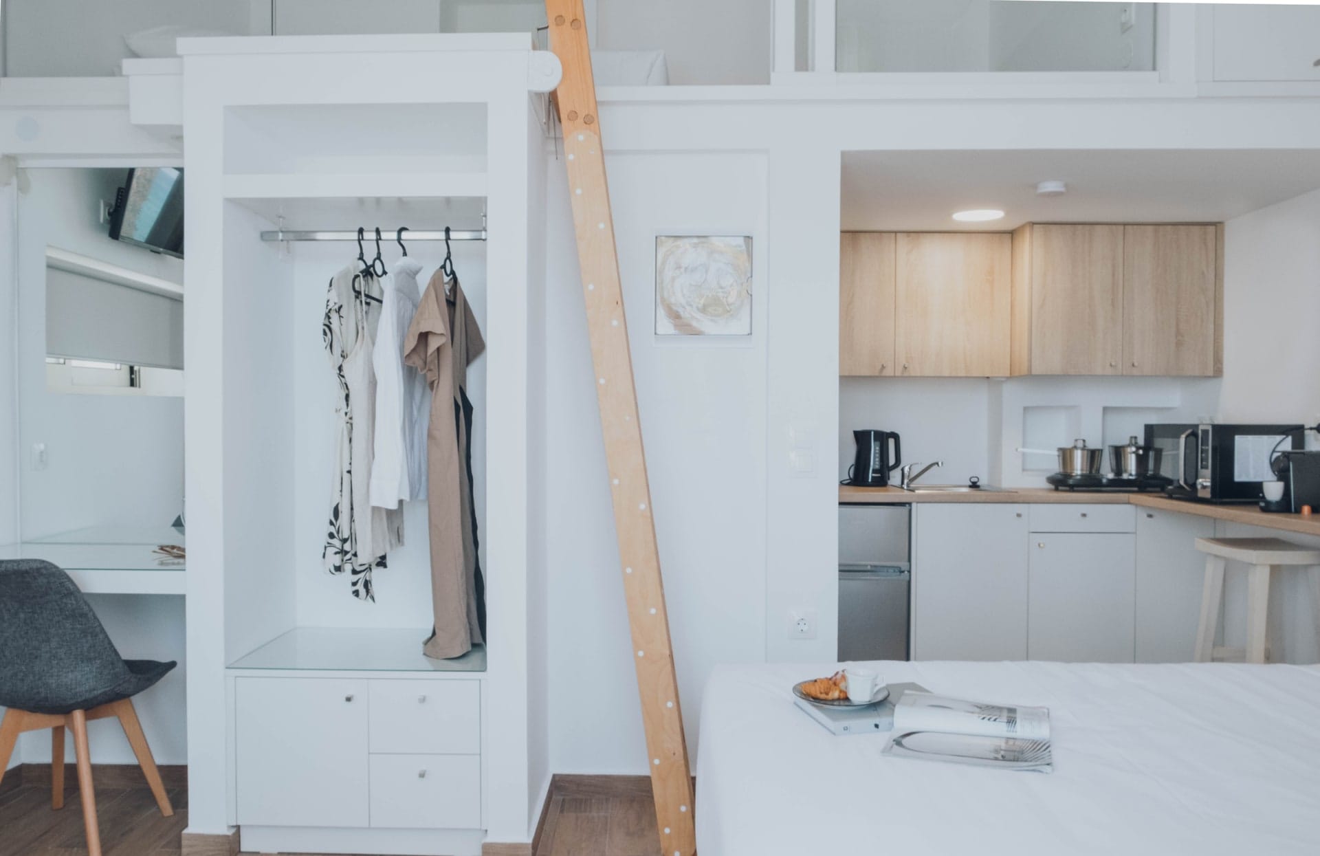 Open wardrobe with robes hanging beside the ladder